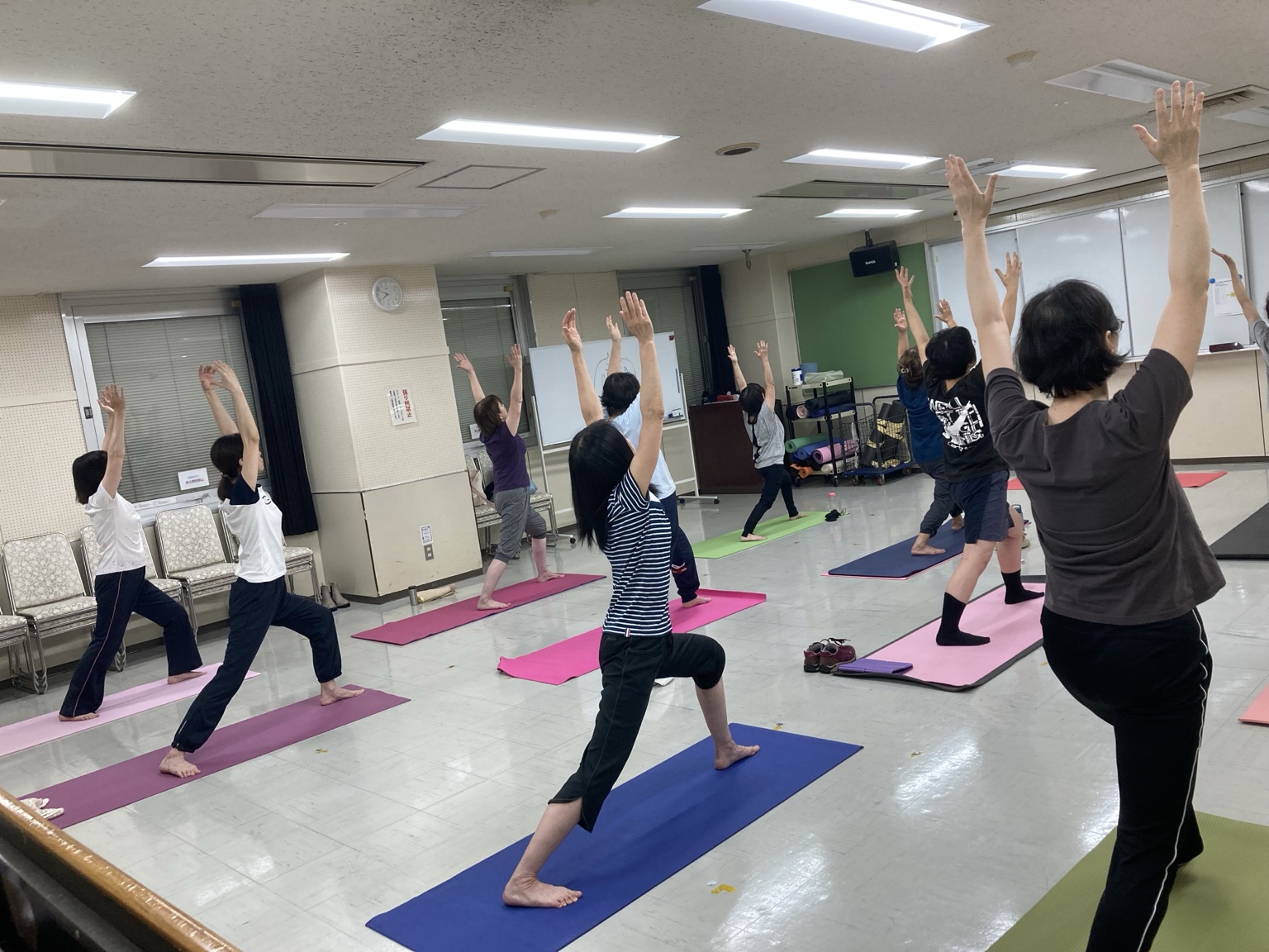 両手を上げてポーズを取るヨガクラスの参加者